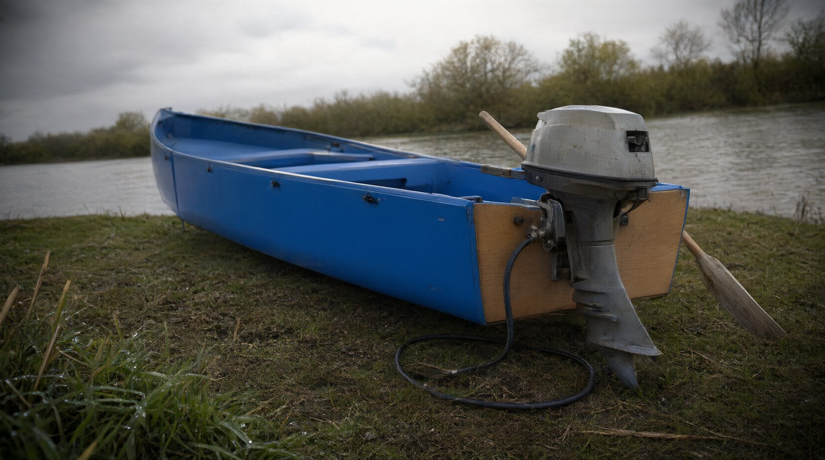 Stern of the folding boat showing the marine plywood transom board with a small outboard motor mounted